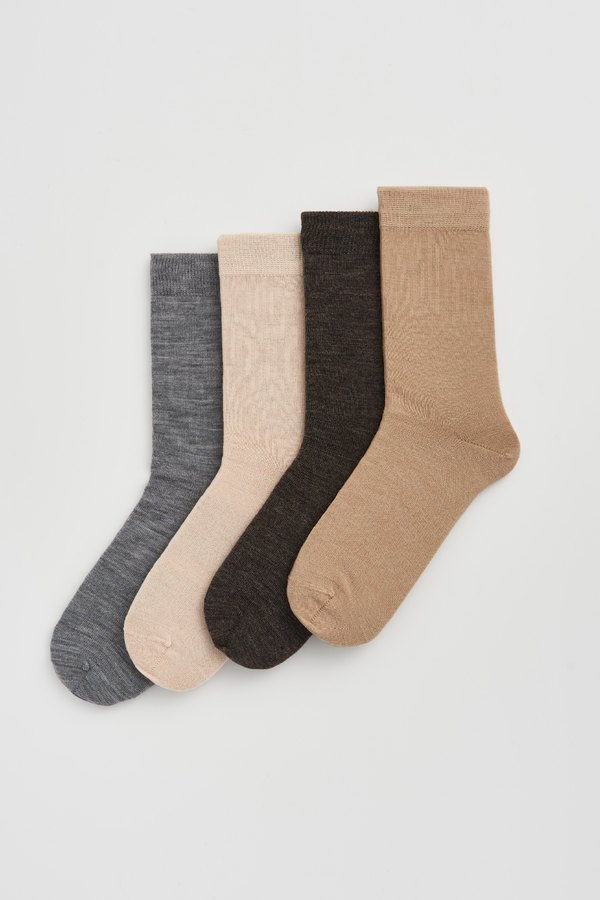 Set of four calf-length merino socks in grey, light beige, dark brown, and beige on a light grey background