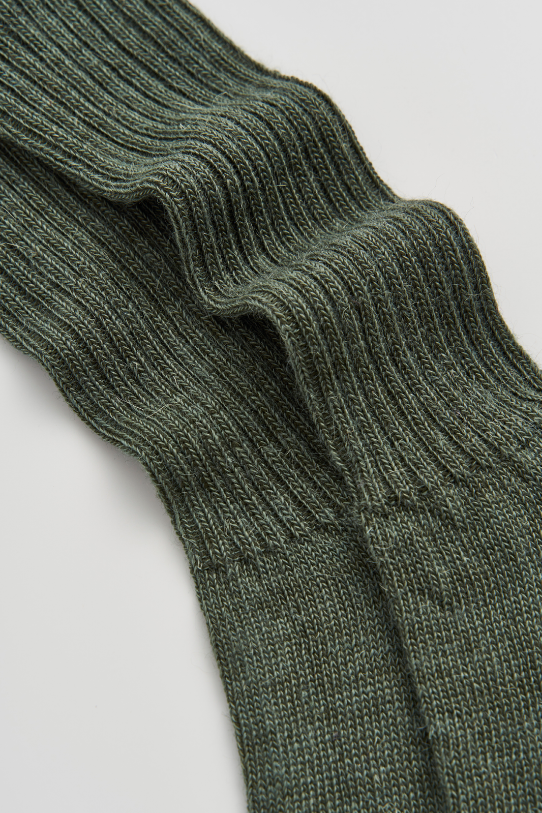 Close-up of a pair of green mohair ribbed socks on a light grey background