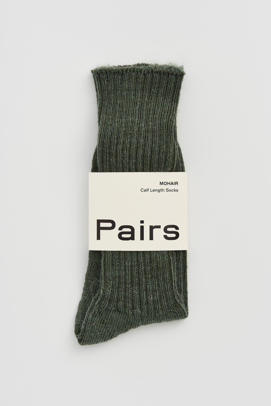Green ribbed mohair sock with a 'Pairs' packaging band on a light grey background
