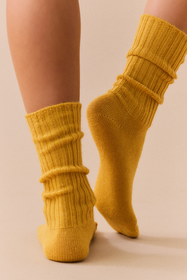 Person wearing mustard yellow ribbed mohair socks on a beige background