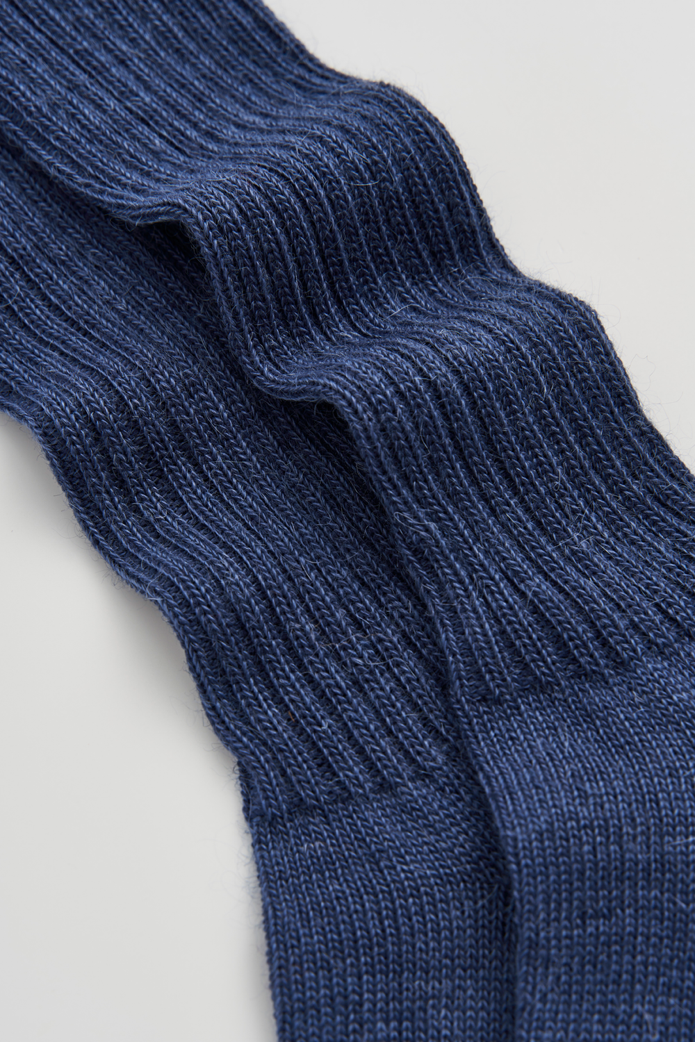 Close-up of a pair of blue ribbed mohair socks on a light grey background