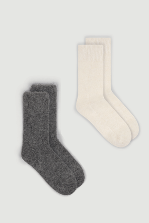 Two pairs of ultra soft plain alpaca bed socks, one grey and one cream, on a white  background.