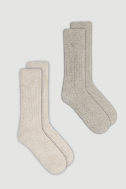 Two pairs of ultra soft ribbed alpaca bed socks, one cream and one light grey, on a white background.