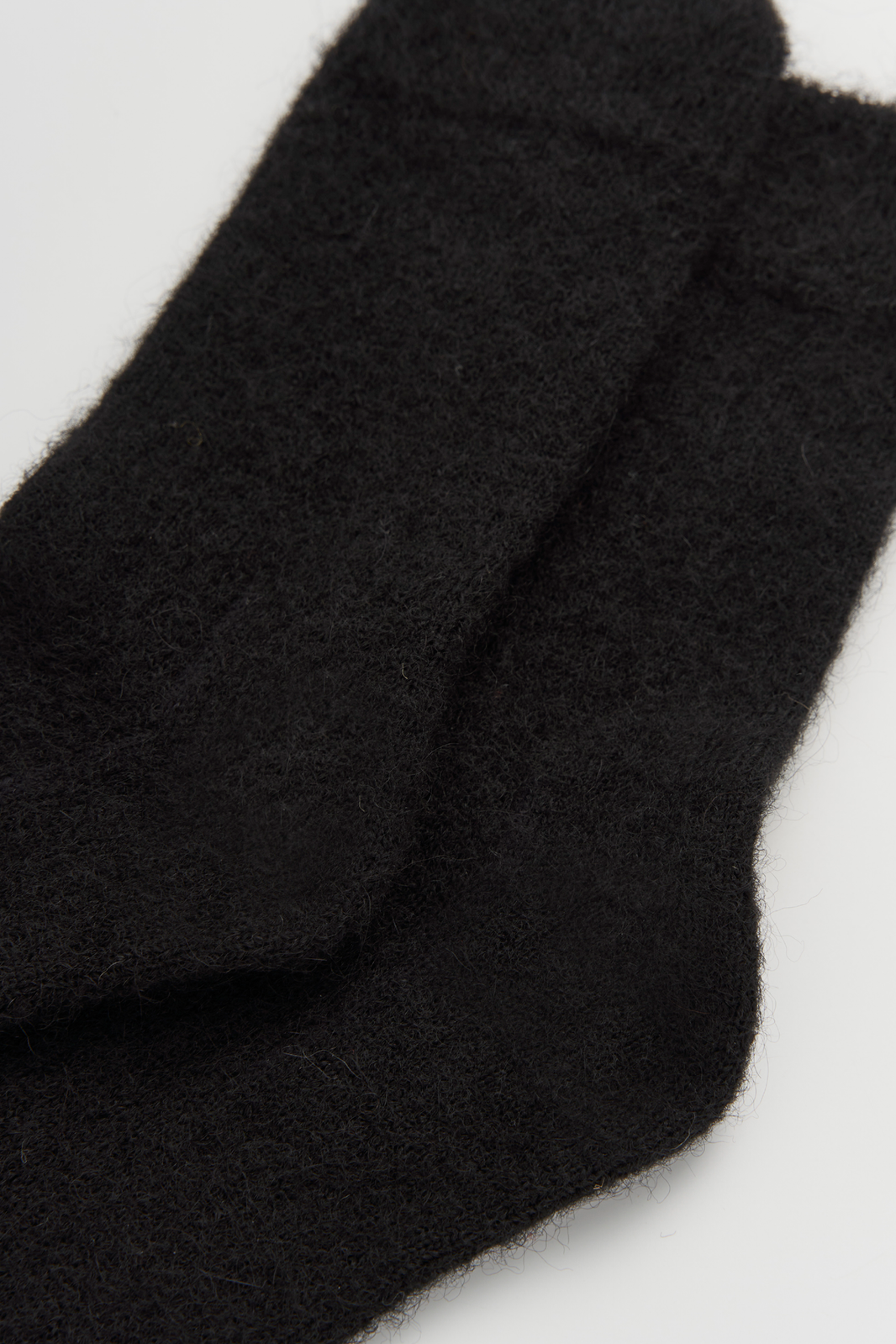 Close-up of black ultra soft alpaca socks on a light grey background