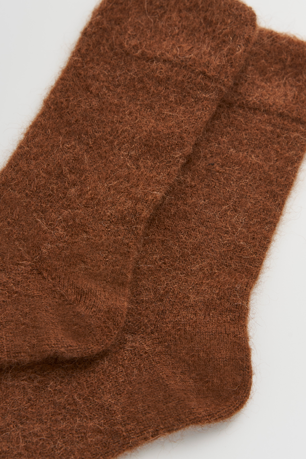 Close-up of a pair of mid-brown ultra soft alpaca socks on a light grey background