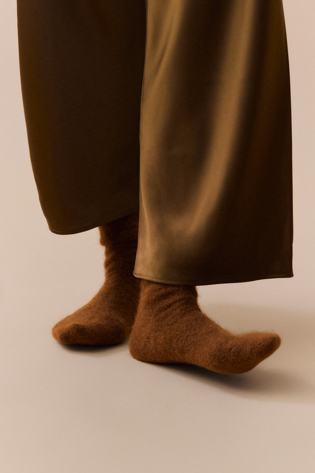 Person wearing bronze trousers and mid-brown ultra soft alpaca socks on a neutral background