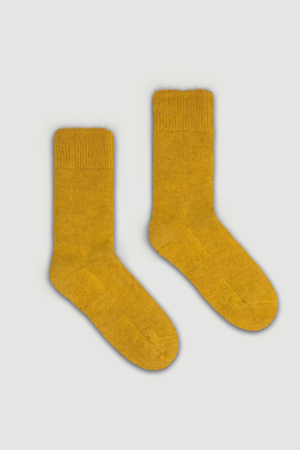 Pair of mustard yellow calf length ultra soft alpaca socks on a light grey background