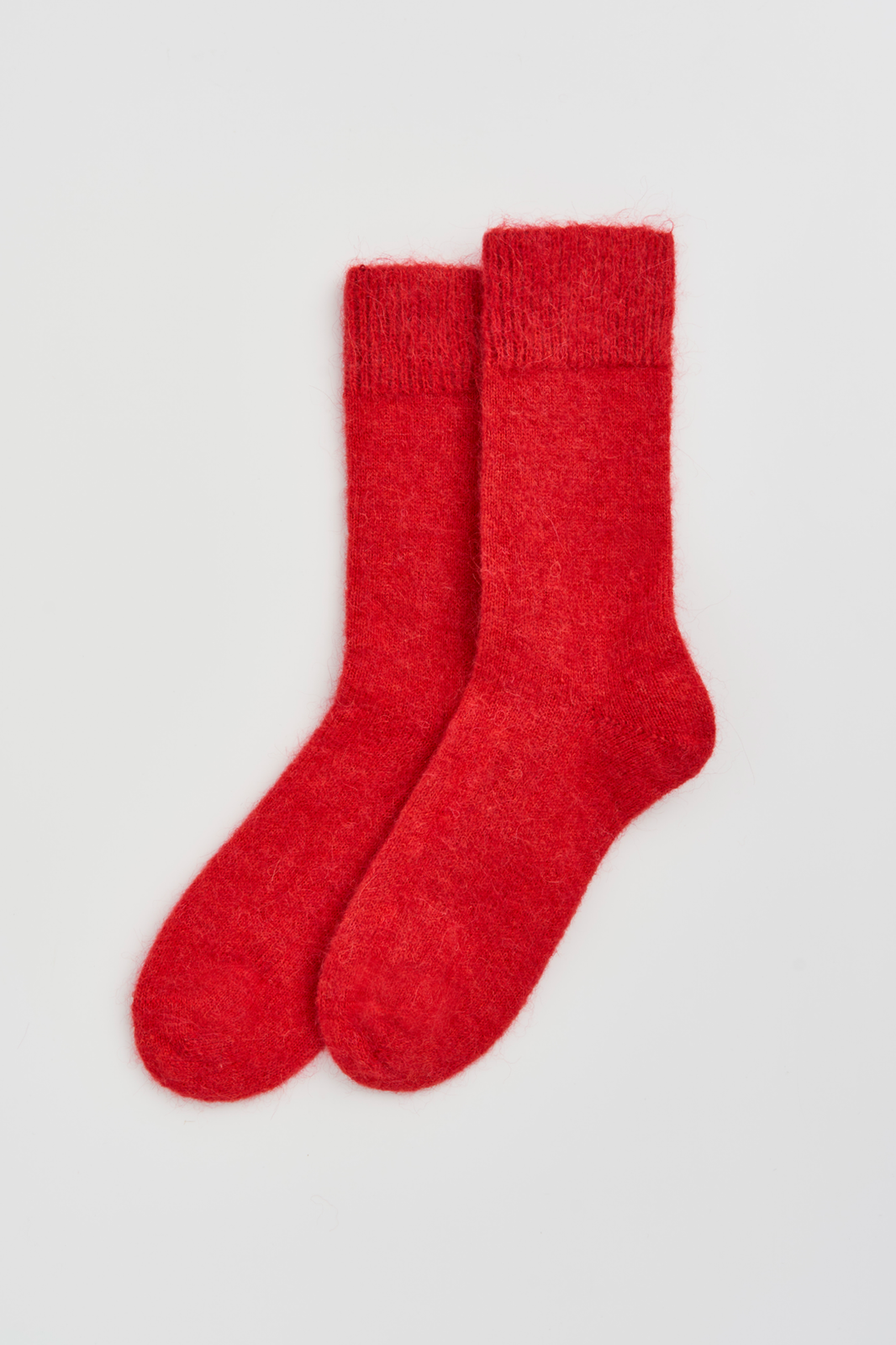Pair of red ultra soft alpaca socks on a light grey background