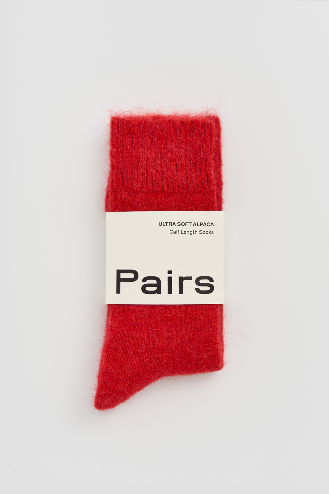 Red ultra soft alpaca socks with a 'Pairs' packaging band on a light grey background