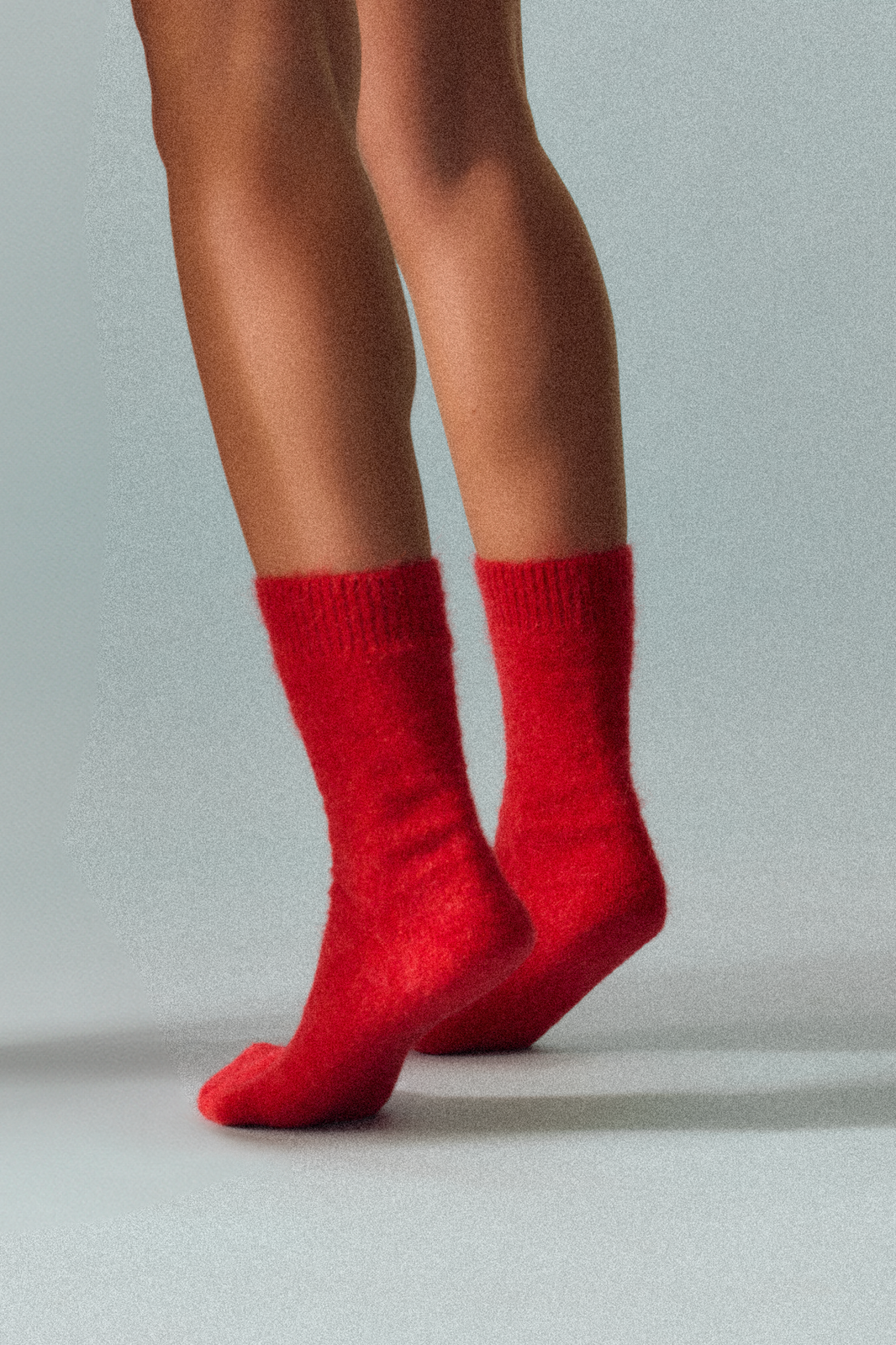 Red ultra soft alpaca socks worn by a person on a light grey background