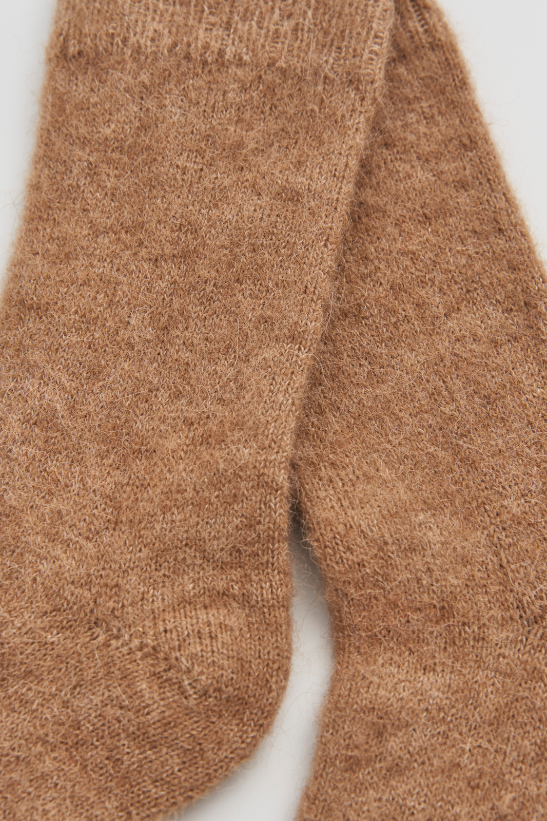 Close-up of a pair of light brown ultra soft alpaca bed socks on a white background