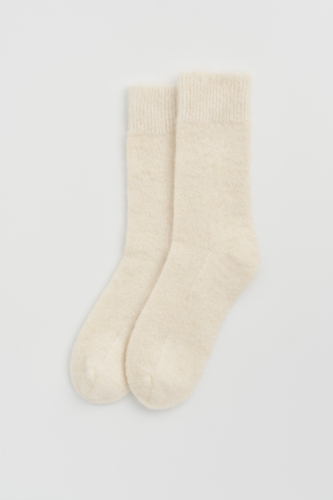 Pair of cream ultra soft alpaca bed socks on a light grey background