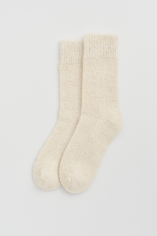 Pair of cream ultra soft alpaca bed socks on a light grey background