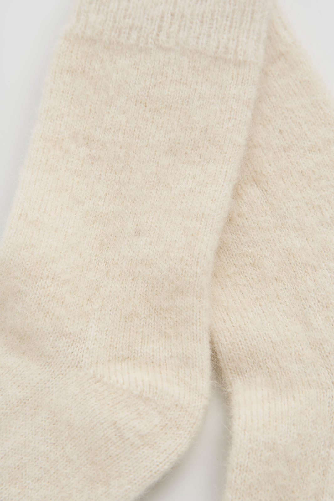 Close-up of a pair of cream ultra soft alpaca bed socks on a white background