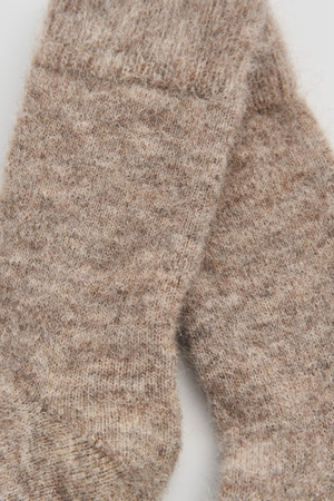 Close-up of a pair of oatmeal ultra soft alpaca bed socks on a white background