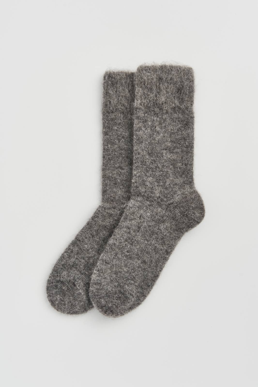 Pair of grey plain ultra soft alpaca bed socks on a light grey background