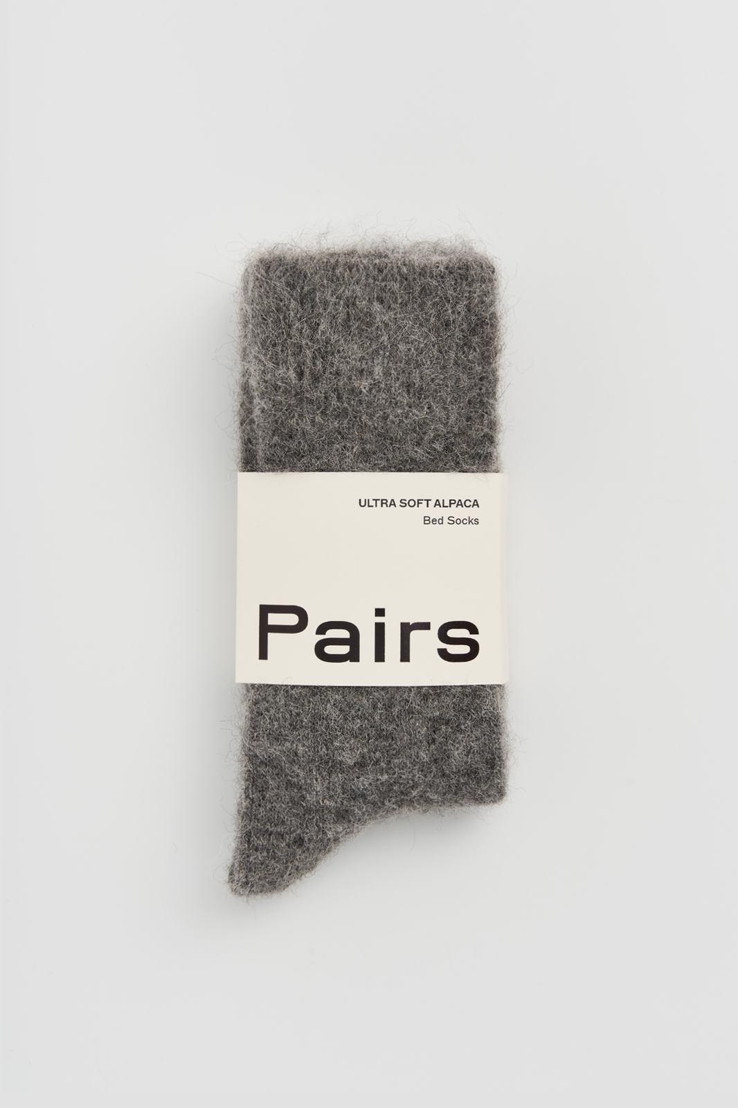 Grey ultra soft alpaca bed sock with a 'Pairs' packaging band on a light grey background