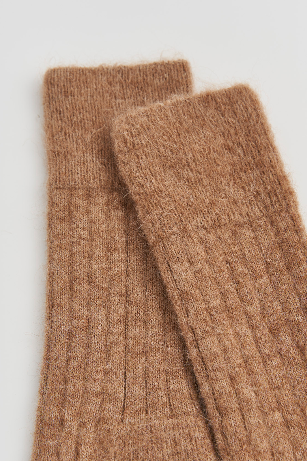 Pair of brown ribbed ultra soft alpaca bed socks on a light grey background