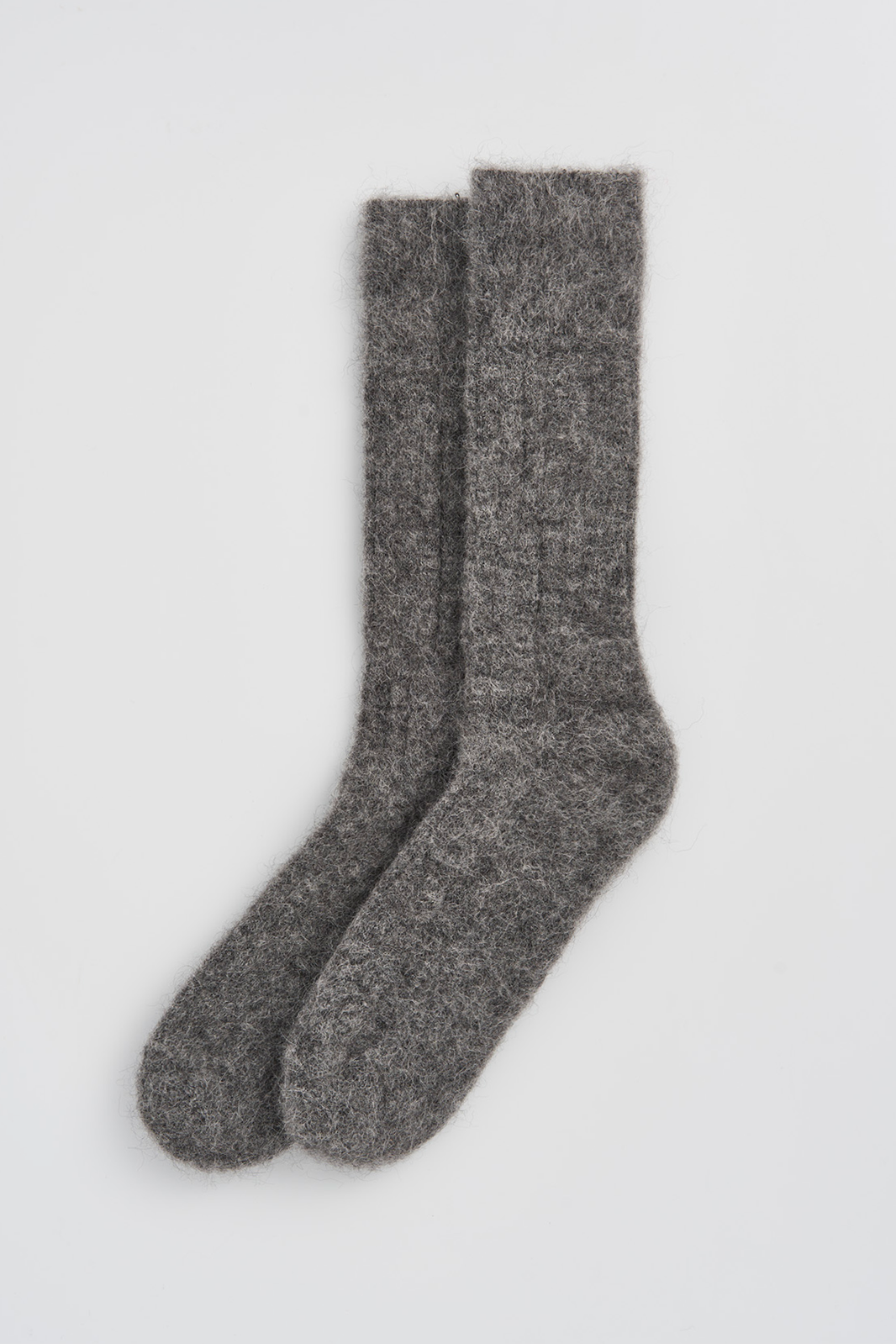 Pair of grey ultrasoft alpaca ribbed bed socks on a light grey background
