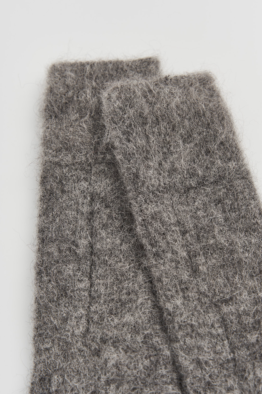 Close-up of the top of a pair of ultrasoft alpaca ribbed bed socks on a light grey background