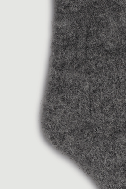 Close-up of the heel of a dark grey ultra soft alpaca ribbed bed sock on a light grey background
