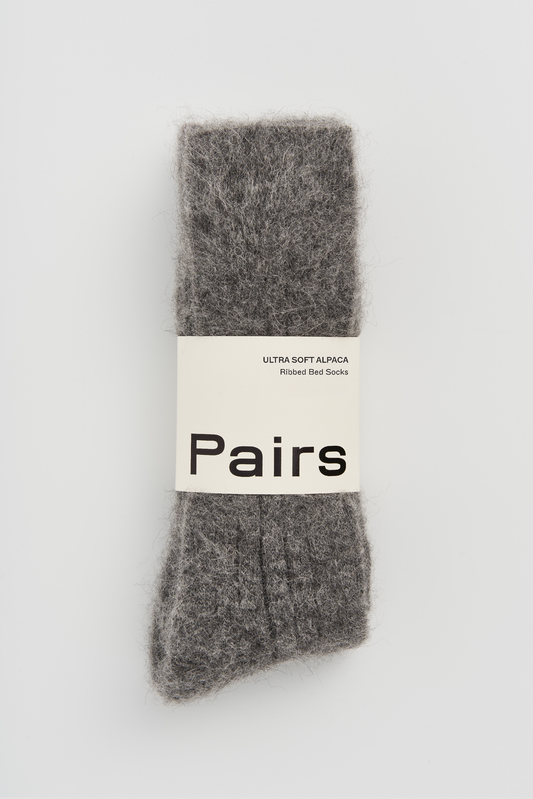 Grey ultra soft alpaca ribbed bed sock with a 'Pairs' packaging band on a light grey background