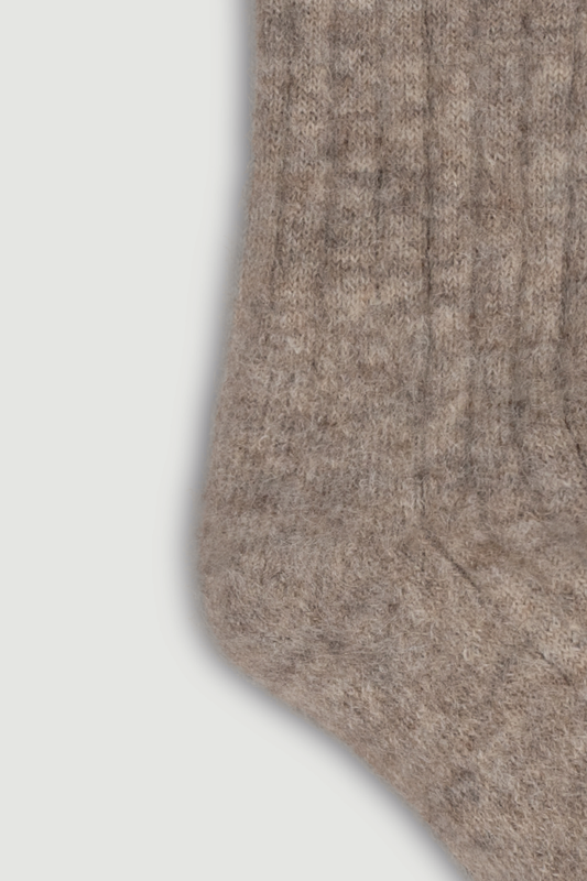 Close-up of the heel of a light brown ultra soft ribbed alpaca bed sock on a white background