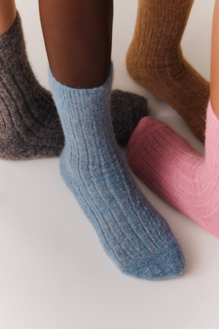 Close-up of various pairs of ultra soft ribbed alpaca bed socks in different colours on a light background.