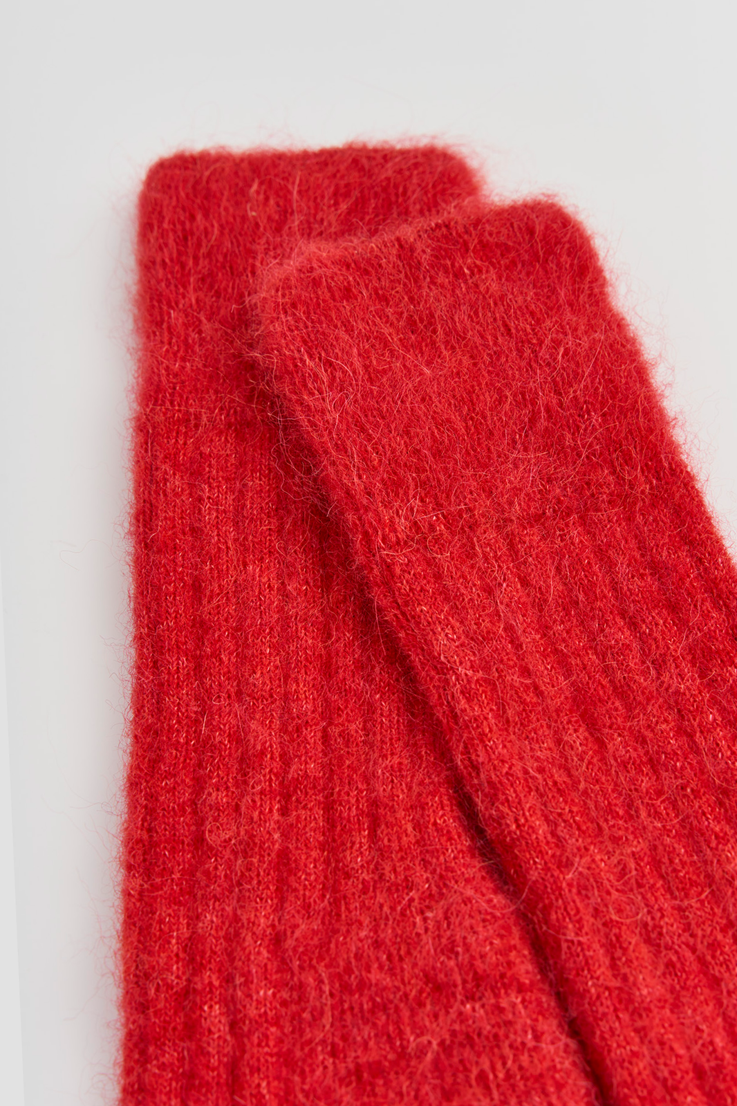 Close-up of the tops of a pair of red ribbed ultra soft alpaca bed socks on a white background