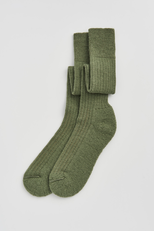 Pair of green wool knee high socks on a light grey background