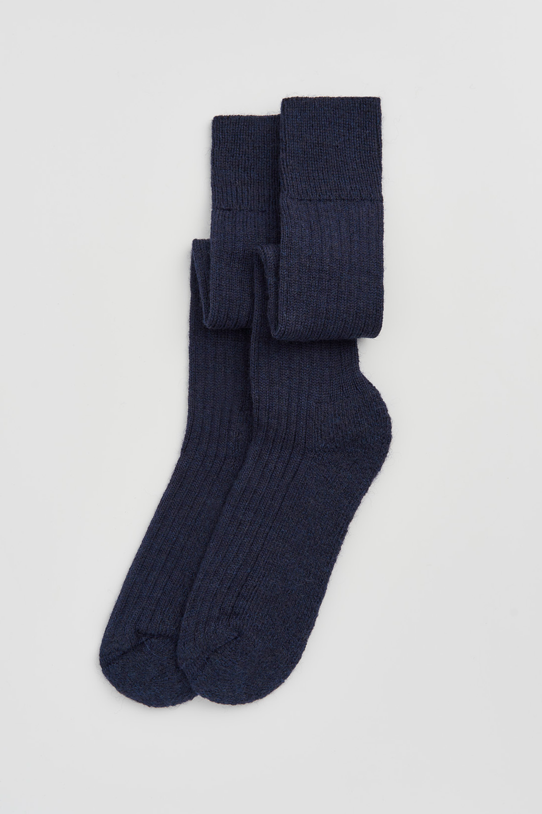 Pair of navy blue wool knee high socks on a light grey background