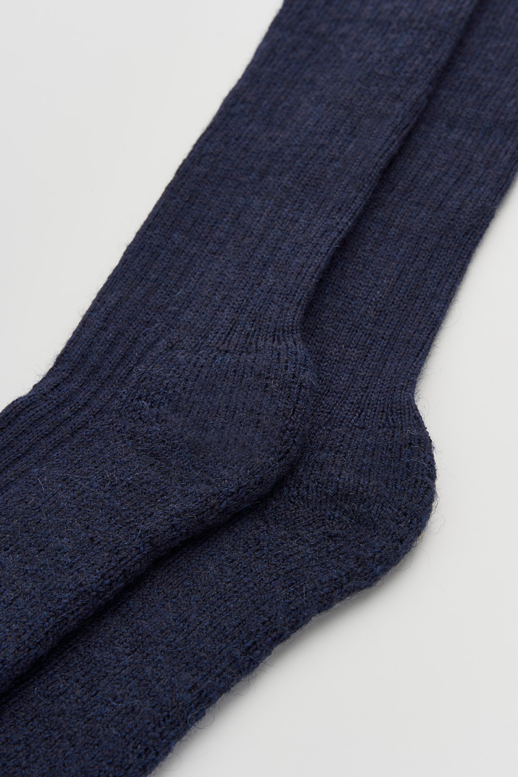 Close-up of a pair of navy wool knee high socks on a light grey background