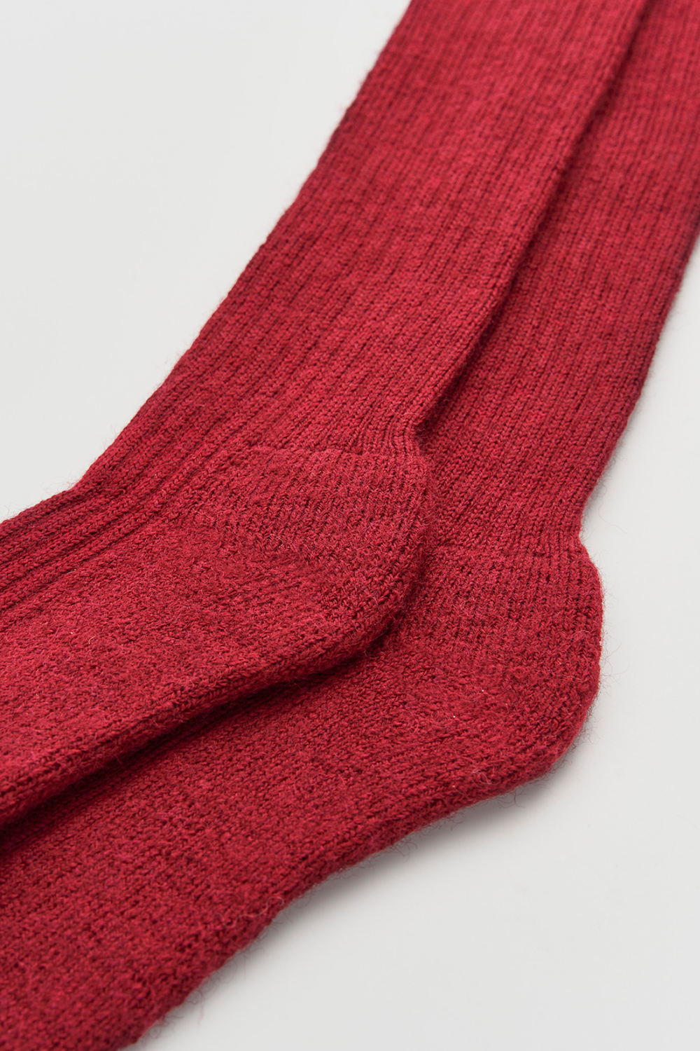 Close-up of a pair of red wool knee-high socks on a light grey background