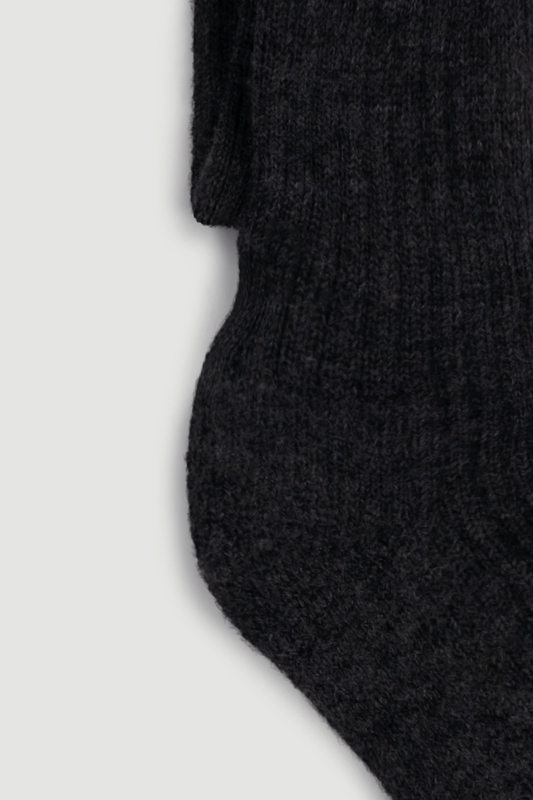Close-up of the heel of a dark grey wool knee high sock on a white background