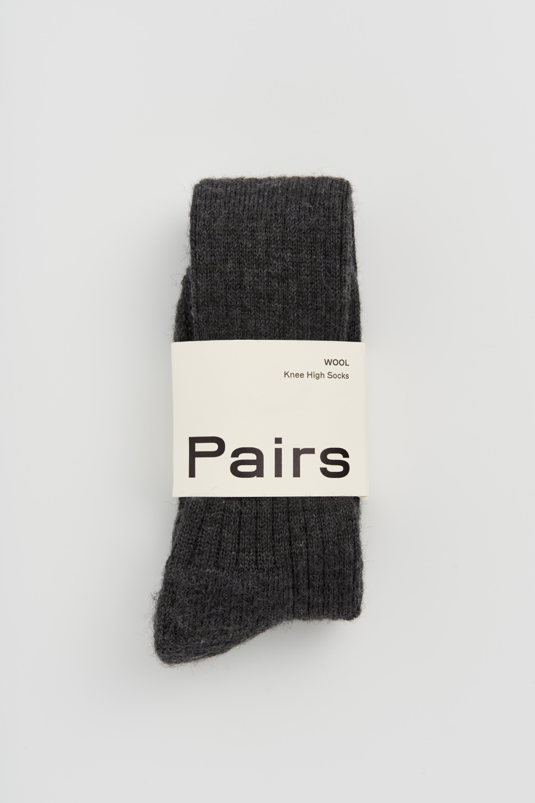 Pair of dark grey wool knee high socks with a 'Pairs' packaging band on a light grey background