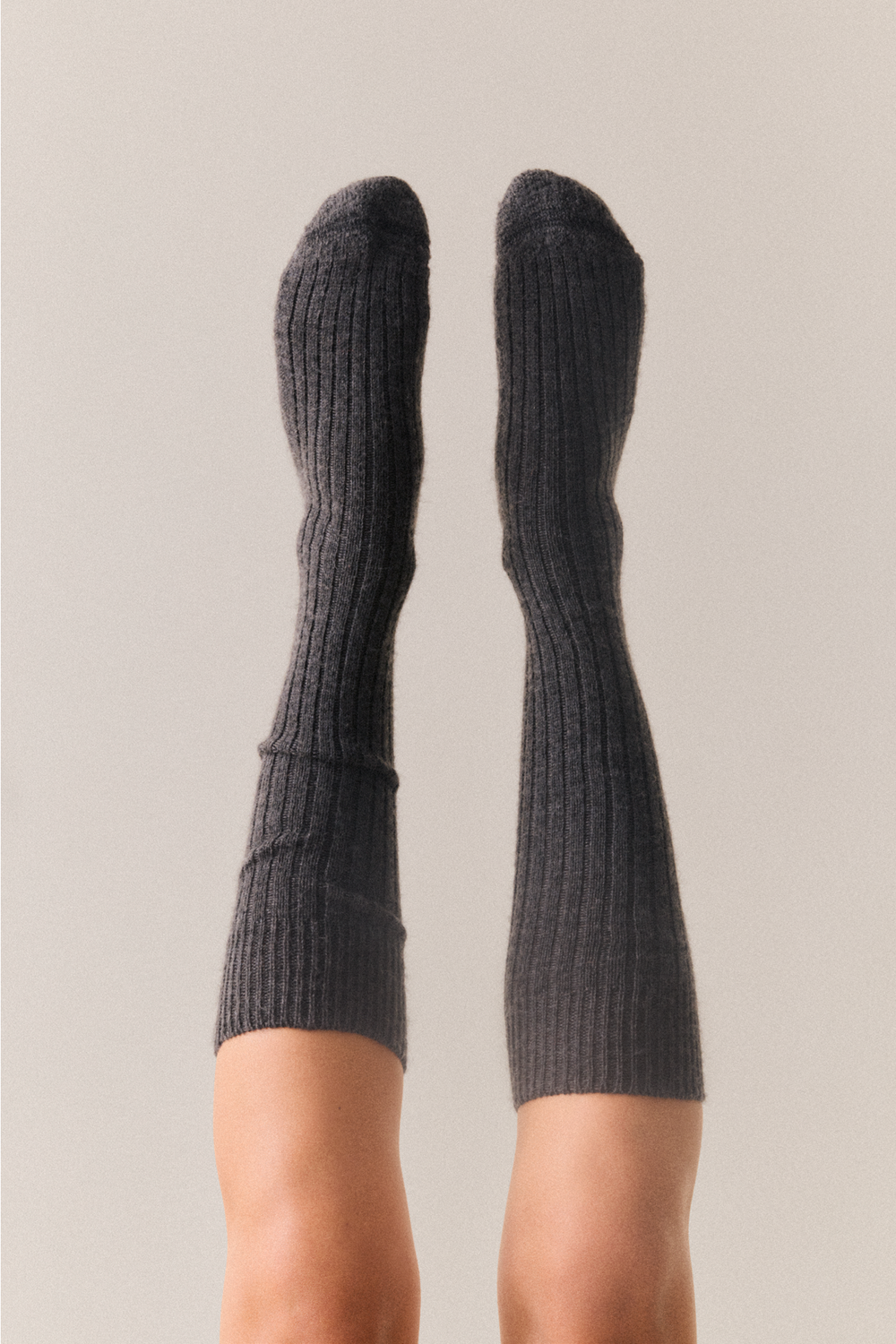 Dark grey wool knee high socks on a neutral background