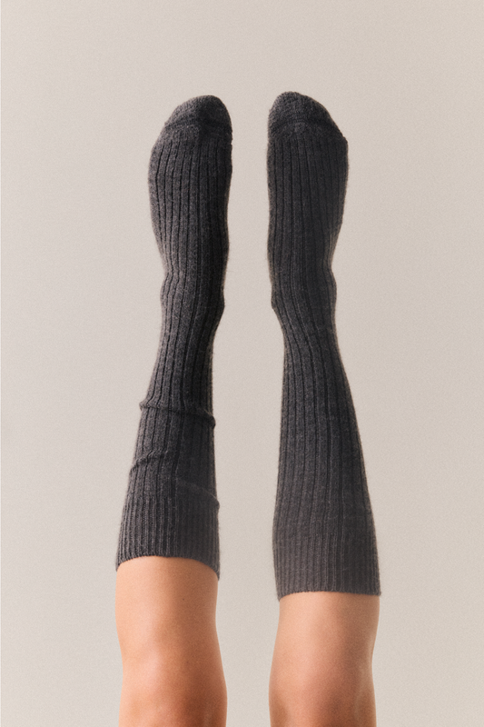 Dark grey wool knee high socks on a neutral background
