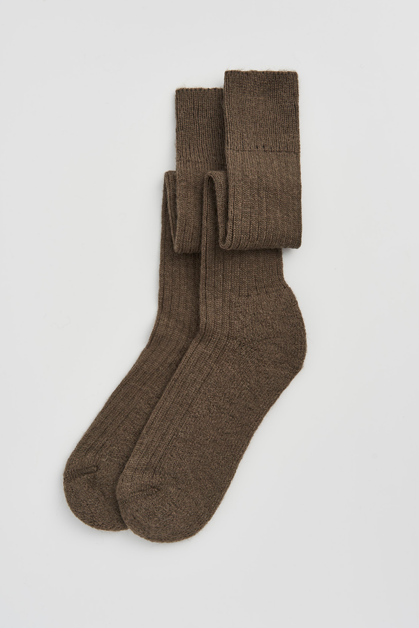 Pair of muddy green wool knee high socks on a light grey background