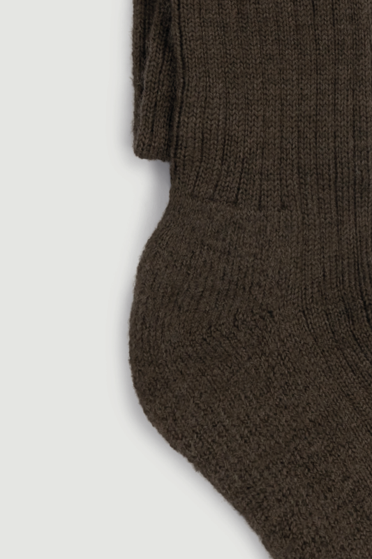 Close-up of the heel of a brown wool knee high sock on a white background