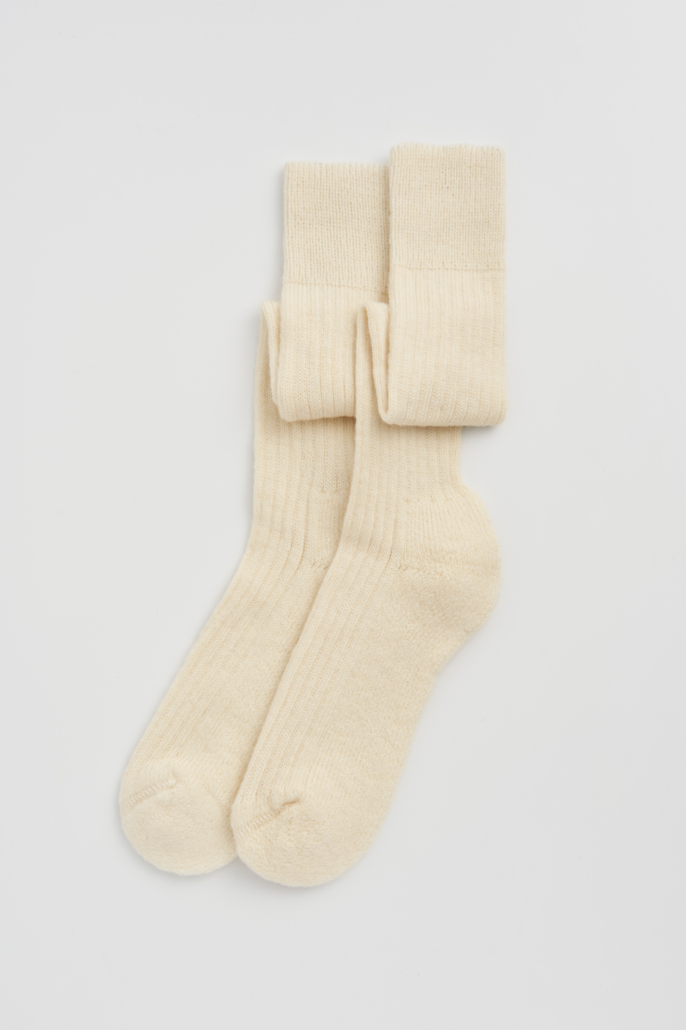 Pair of cream wool knee high socks on a light grey background