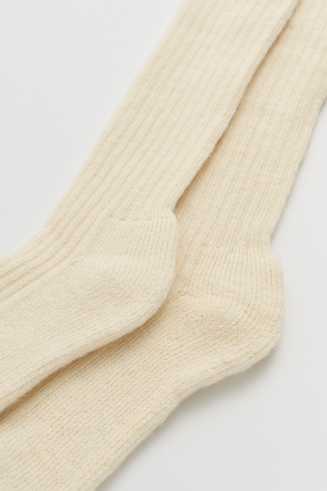 Close-up of a pair of cream wool knee high socks on a light grey background