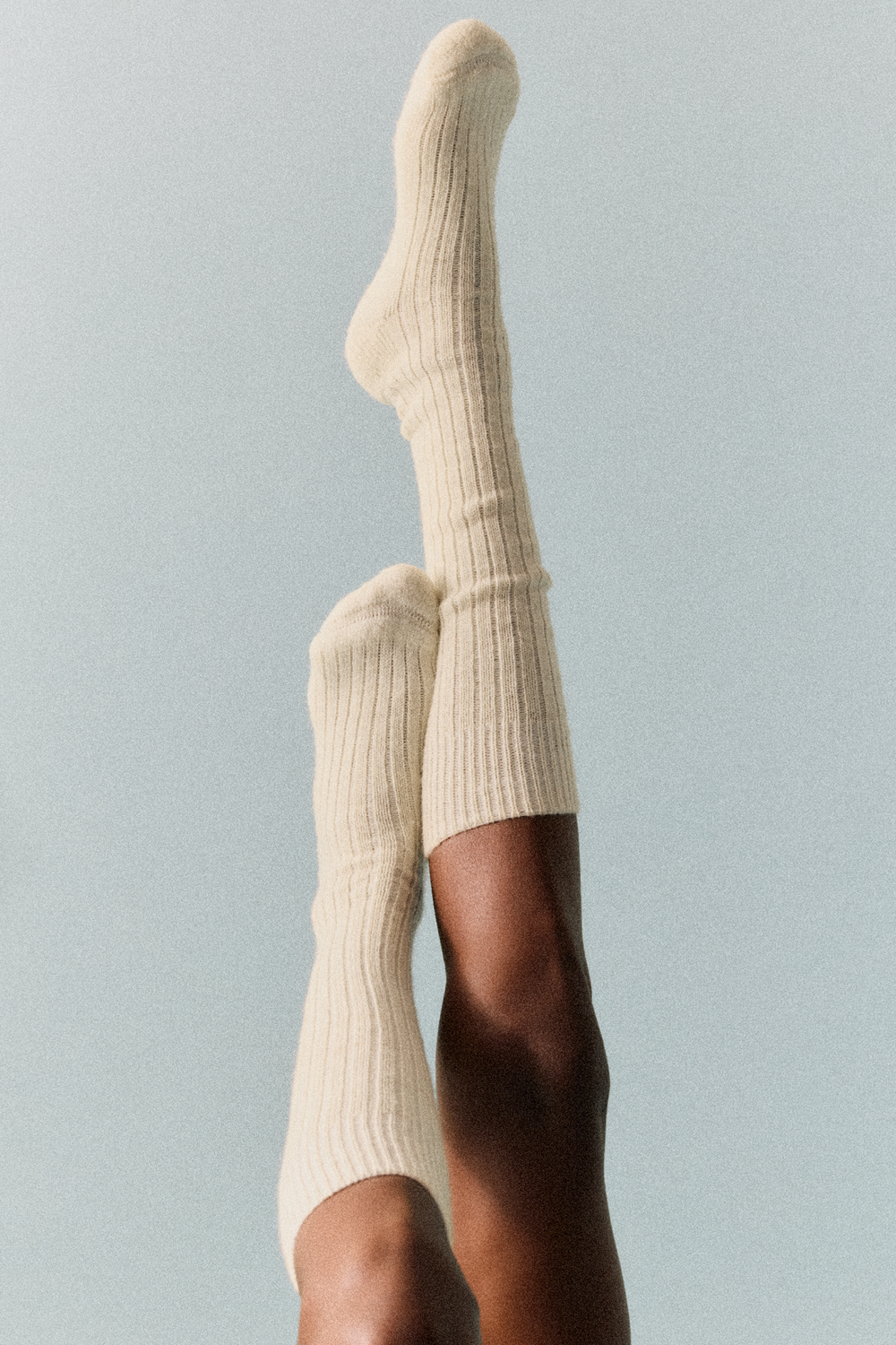 Person wearing cream wool knee high socks against a light grey background
