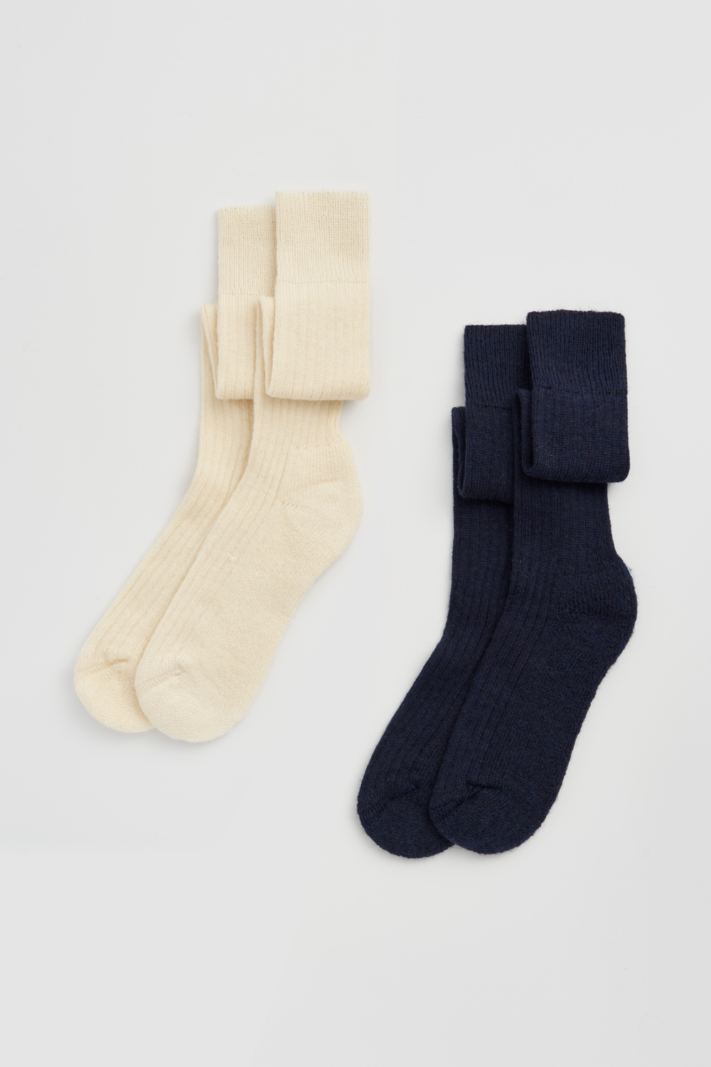 Two pairs of wool knee high socks, one cream and one navy, on a light grey background.