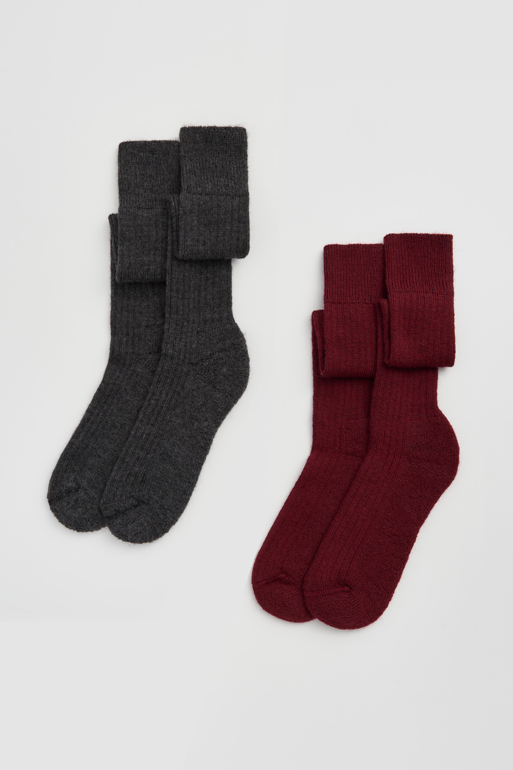 Pair of grey wool knee high socks and pair of burgundy wool knee high socks on a light grey background